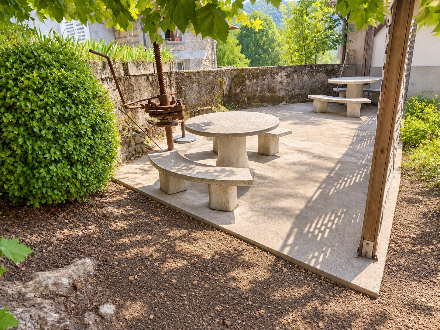 Espace extérieur du gîte avec tables et bancs à l’ombre de la végétation